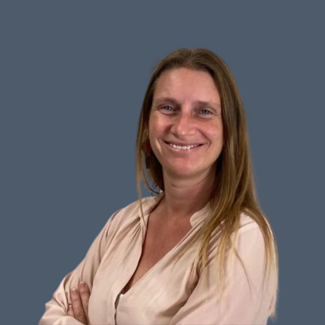 Vrouw met lange steile haren en lichte huid draagt lichte blouse; armen gekruist, donkerblauwe achtergrond